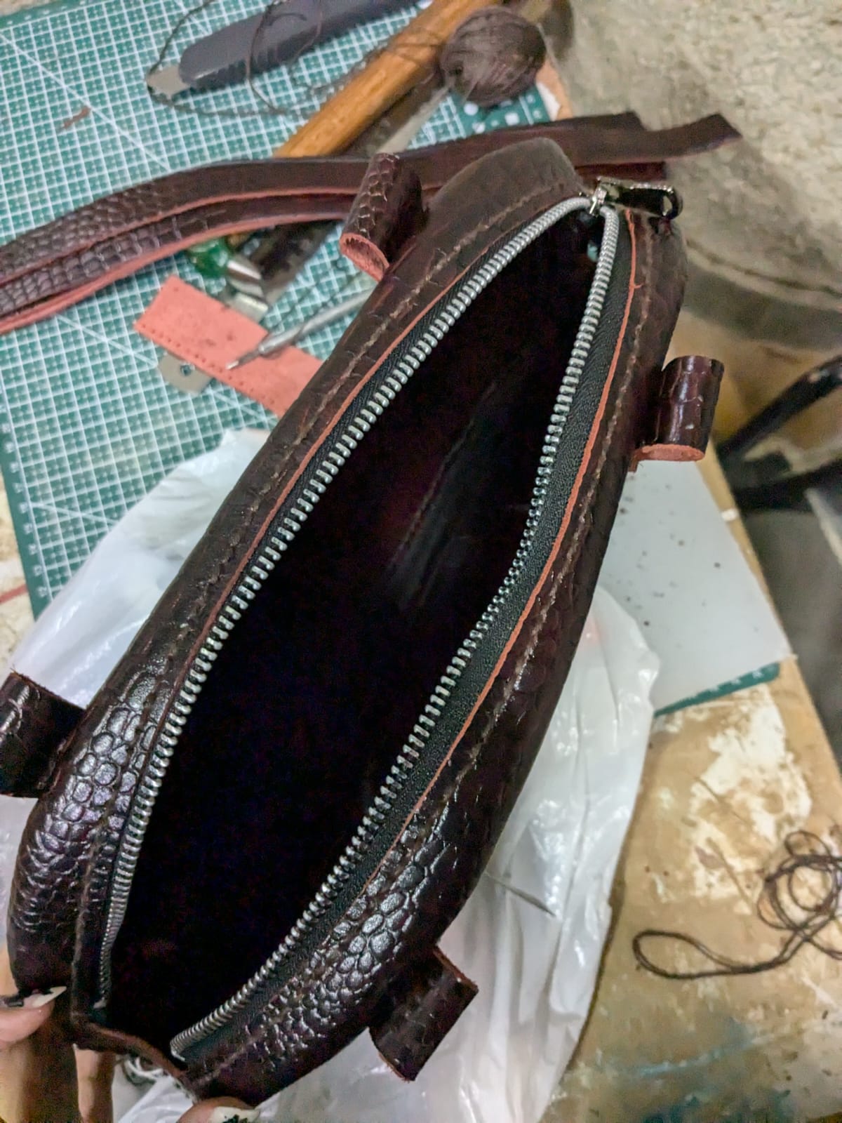 Open top view of the leather purse showing stitching progress and interior structure